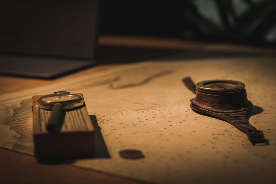 A vintage compass and magnifying glass on an old nautical map evoke a sense of adventure and discovery.